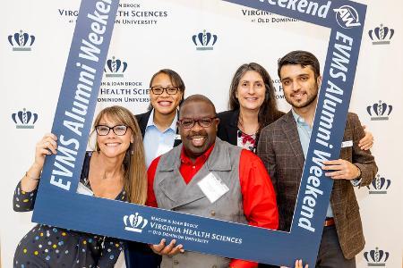 Alumni pose in an EVMS Alumni photo frame