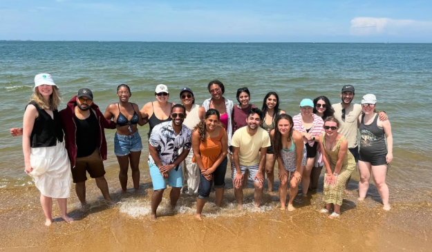 Group shot of residents on the beach with the ocean behind them