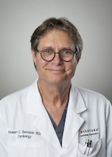 man with glasses wearing white lab coat, smiling