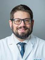 David Lieb, MD, smiles at the camera wearing his white coat and tie. 2021